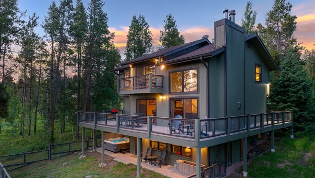 Una casa de dos pisos con balcón, mobiliario exterior y un jacuzzi.