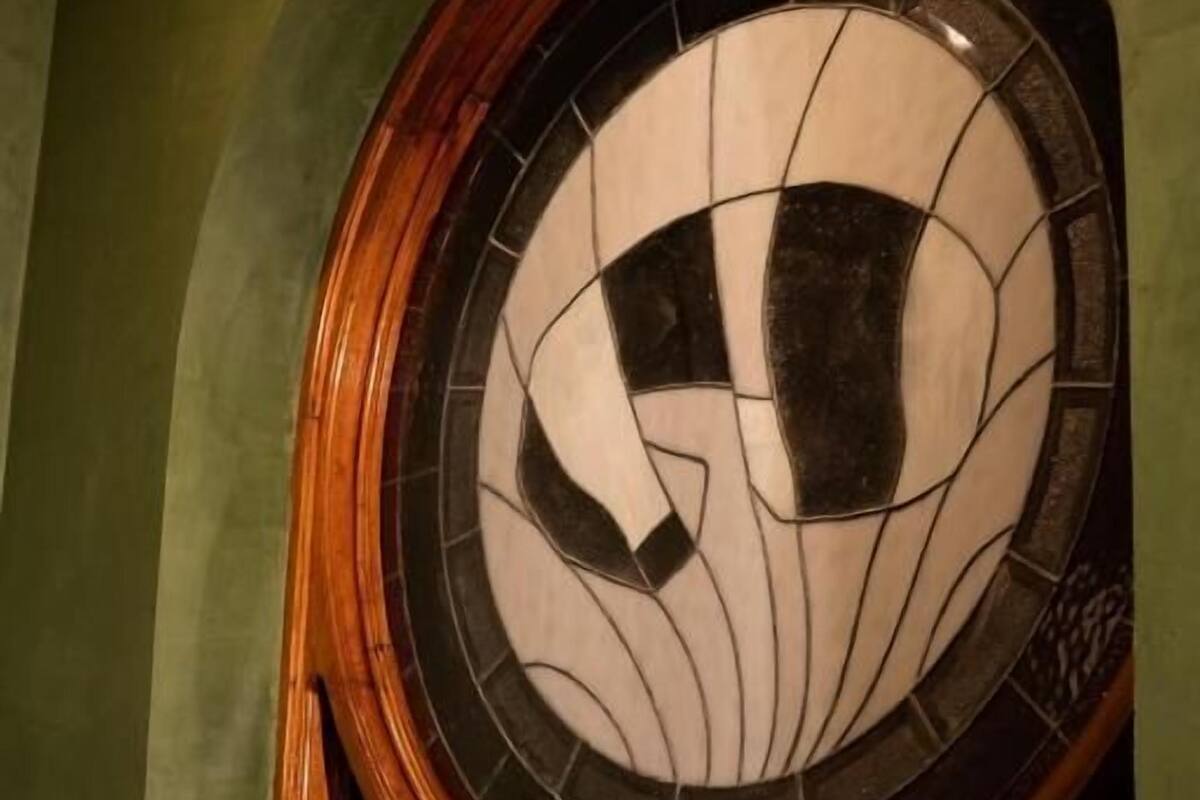 A circular stained glass window with a geometric pattern, set within an arched wooden frame.