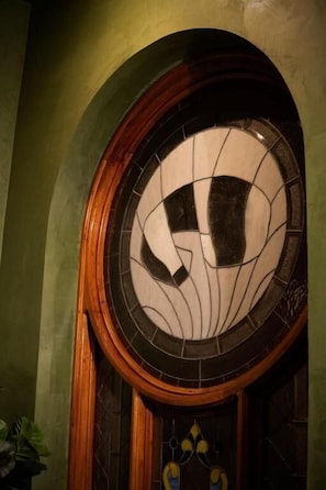 A circular stained glass window with a geometric pattern, set within an arched wooden frame. - Hush Hush (Barranquilla)