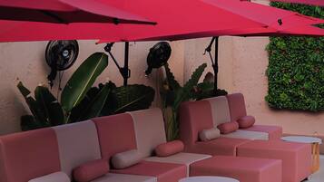 Una piscina al aire libre, sombrillas, sillones reclinables de piscina