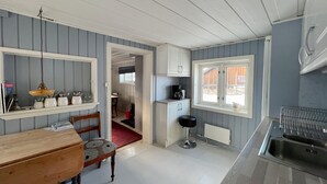 Une cuisine compacte avec un coin repas, un petit tabouret de bar et une fenêtre donnant sur un beau paysage.