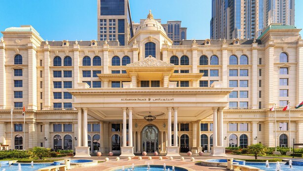 A grand building with a central entrance, multiple windows, and a fountain in front.