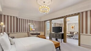 A hotel room with a large bed, a desk, a television, and a seating area with a sofa and chairs.