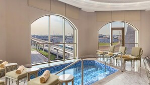 A luxurious indoor pool area with a view of a cityscape, including a bridge and buildings.
