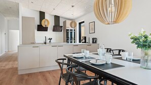 Ett modernt kök med en central köksö, svarta stolar och ett matbord med plats för fyra personer.