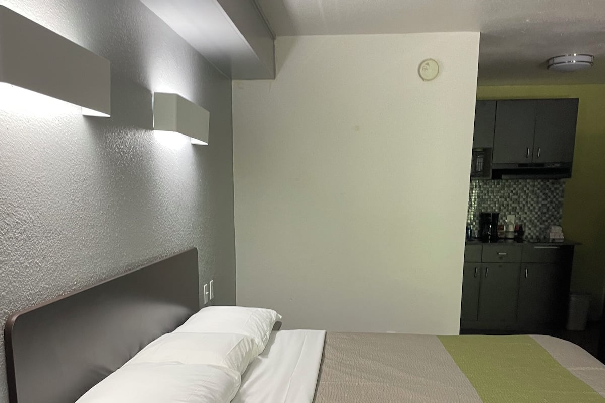 A single bed with a headboard, a bedside telephone, and a nightstand.