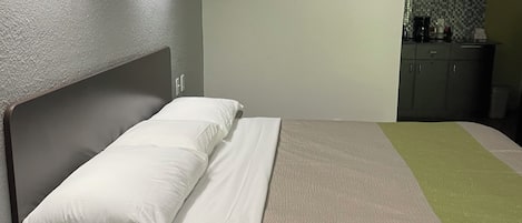 A single bed with a headboard, a bedside telephone, and a nightstand.
