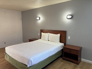 Un dormitorio con cama, mesitas de noche y una lámpara fijada a la pared.