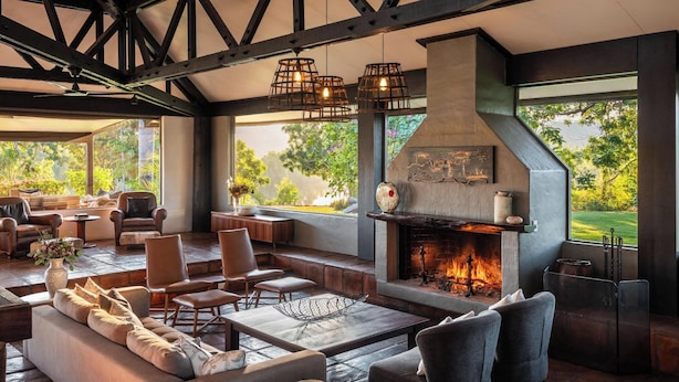 A spacious living area with a fireplace, comfortable seating, and large windows offering a view of the outdoors. - El Questro - Homestead (Durack)