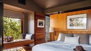 A modern bedroom with a large bed, a seating area with a view, and wooden paneling. - El Questro - Homestead (Durack)