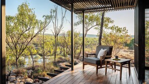 A wooden deck with a bench and table, overlooking a natural landscape with trees and a body of water. - El Questro - Homestead (Durack)