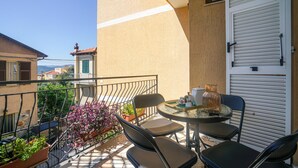 Ein Balkon mit Tisch und Stühlen, Blumentöpfen und Blick auf die umliegenden Gebäude.