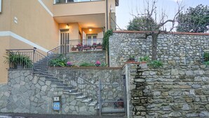 Eine Steintreppe führt zu einem Balkon mit Blumentöpfen und Blumen.