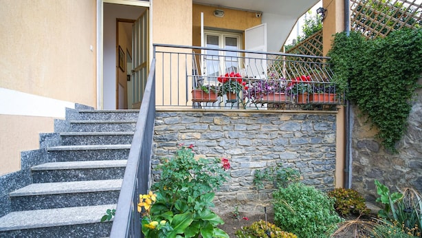 Eine Steintreppe führt zu einem Balkon mit Blumentöpfen und Blumen.