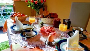 A breakfast table set with plates, cups, a vase of flowers, and various food items. - Apartment Ilona – Modern & Cozy Stay Just 5 Minutes from the Fashion Outlet (Zweibrücken)