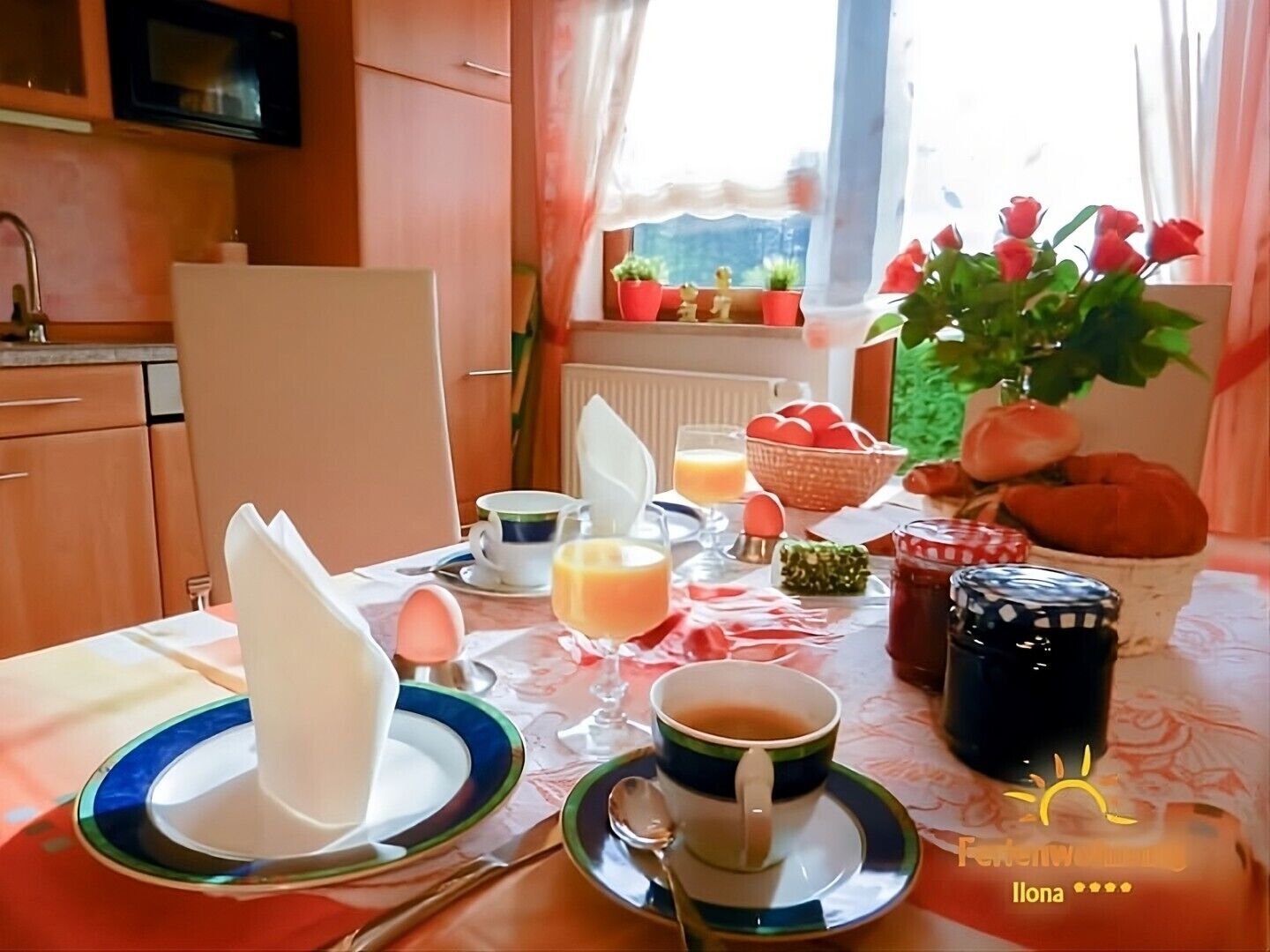 A breakfast table with plates, cups, and a vase of flowers.