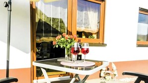 A table with two wine glasses and a vase of flowers on a balcony. - Apartment Ilona – Modern & Cozy Stay Just 5 Minutes from the Fashion Outlet (Zweibrücken)
