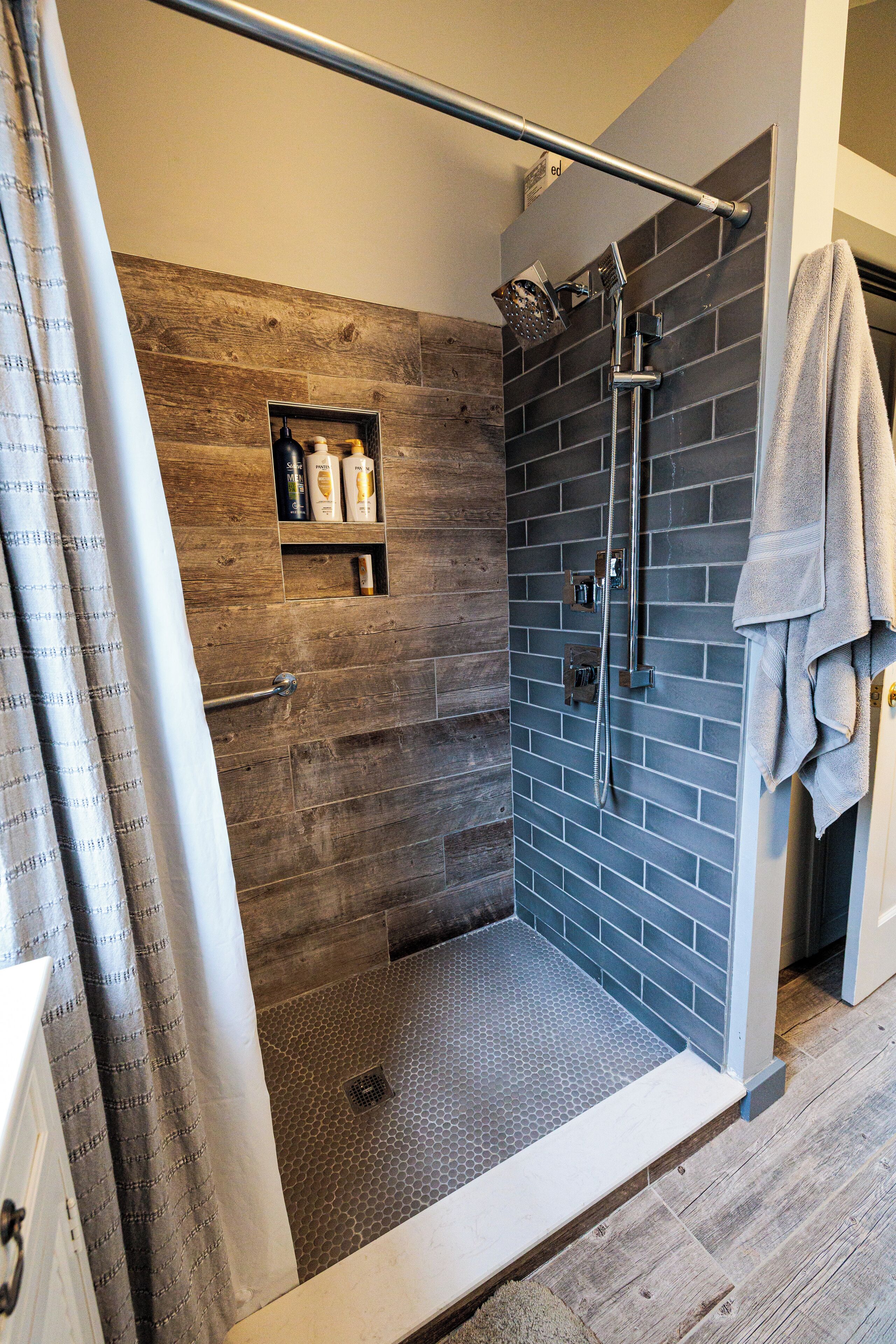 A shower with a rain showerhead, a towel rack, and a shelf with toiletries.