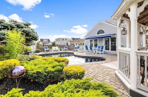 A pool area with lounge chairs, a gazebo, and a well-maintained garden.