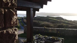 A stone structure with a view of a coastal landscape and a body of water. - The Roundhouse - Bliss by the sea (Lettermullen)