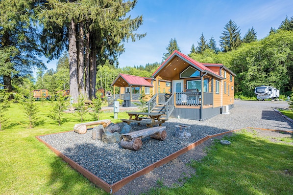 Une cabane avec une terrasse, un foyer et un espace recouvert de gravier.