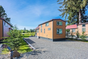 Un bâtiment à deux étages, avec un toit rouge, entouré de gravier et de verdure.