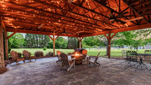 Une terrasse extérieure avec des chaises en bois, une table et un foyer.