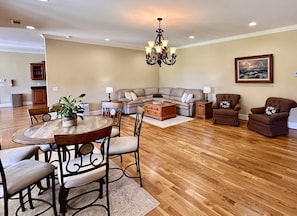 A spacious living room with a dining area, a chandelier, and a painting on the wall.