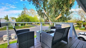 A balcony with wicker furniture and a view of a street and trees. - Modern Apartment Near Downtown Sac (West Sacramento)