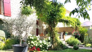Ein Garten mit einem runden Tisch und einem Stuhl, umgeben von verschiedenen Pflanzen und Blumen.