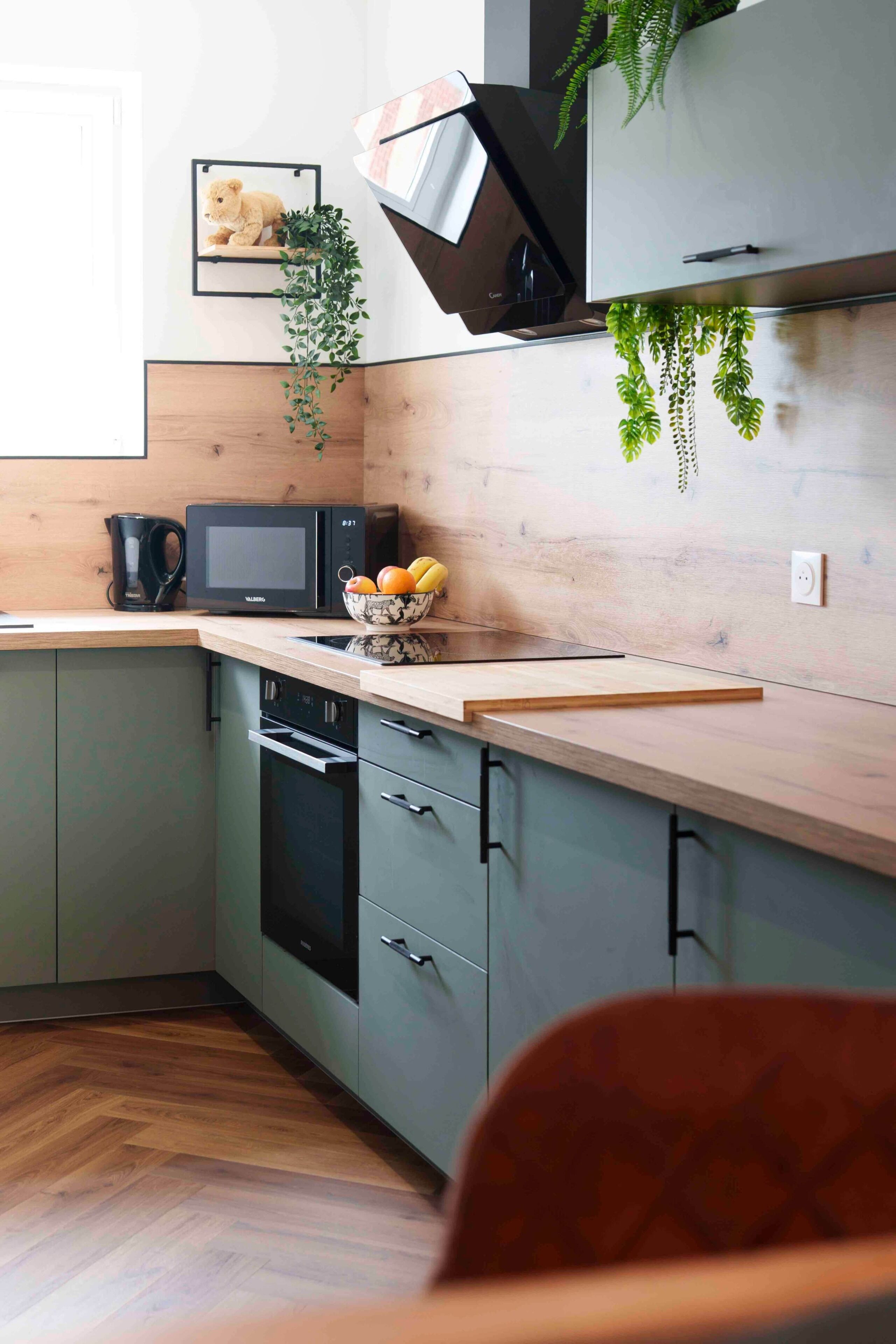 A modern kitchen with a microwave, coffee maker, and a fruit bowl on the counter.