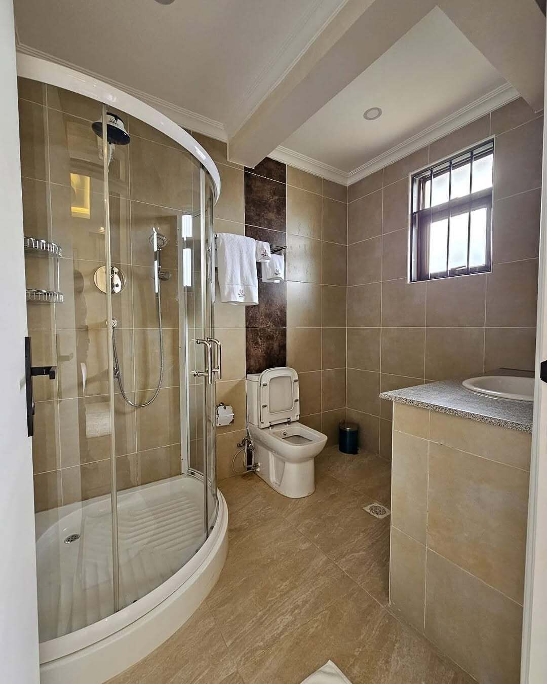 Un baño moderno con ducha acristalada, inodoro y lavamanos.