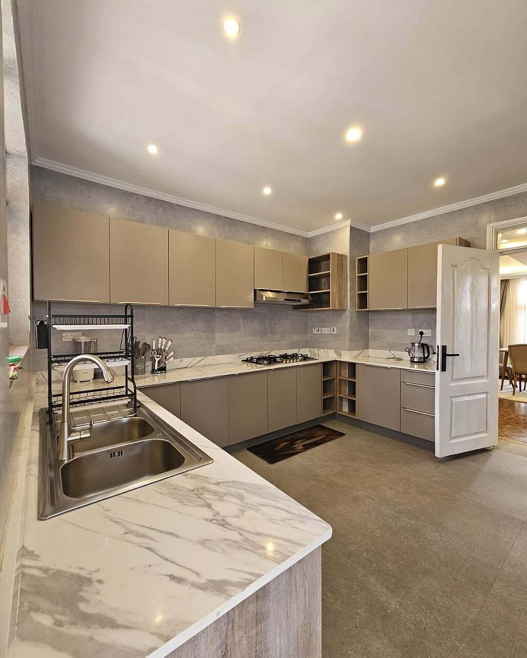 A modern kitchen with a marble countertop, stainless steel sink, and built-in cabinets.