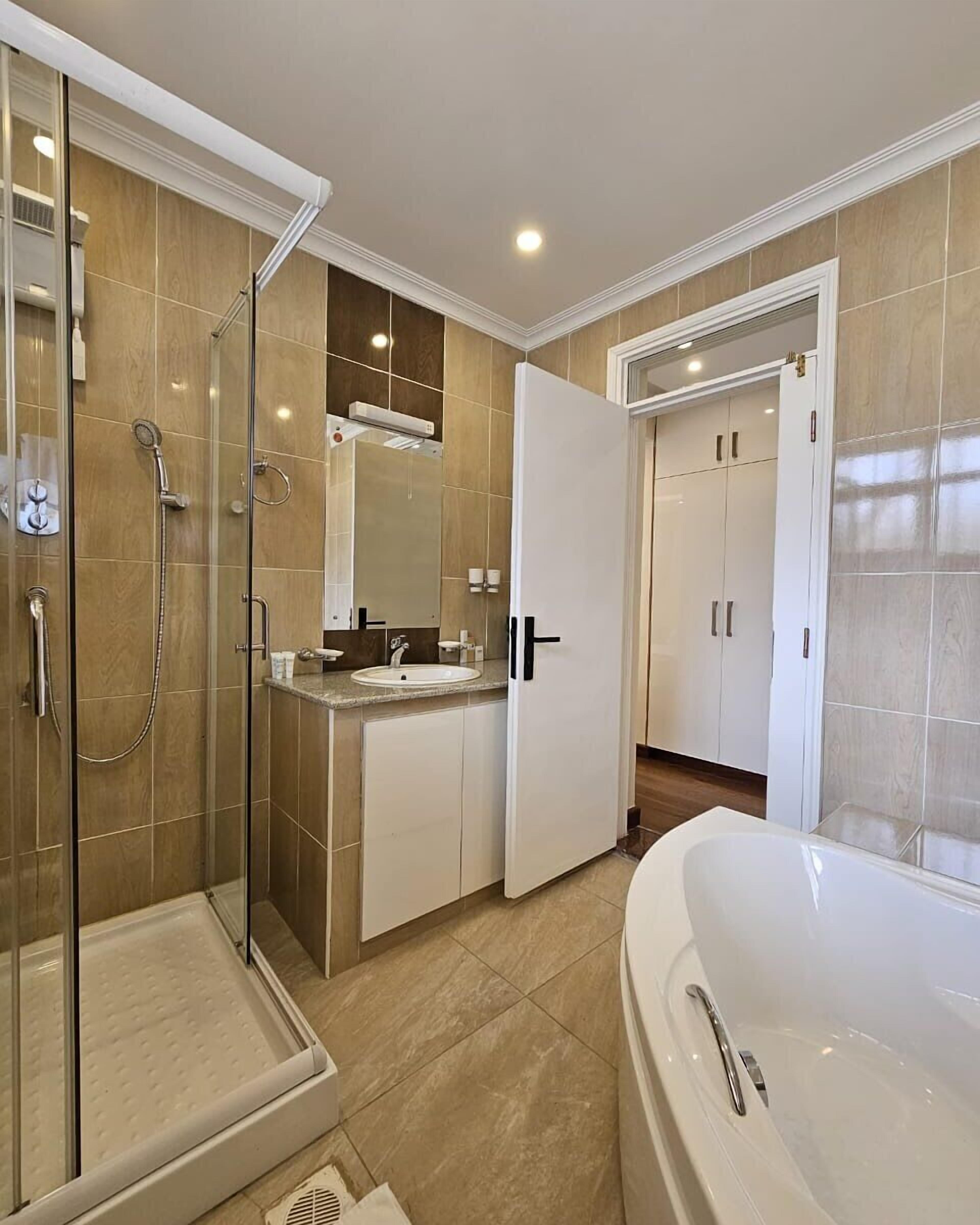A modern bathroom with a glass shower enclosure, a freestanding bathtub, and a vanity with a sink and mirror.