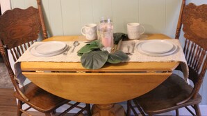 Een eettafel gedekt met borden, een karaf en een kaars.