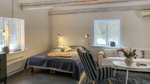 Une chambre à coucher avec un lit, des lampes de chevet, une chaise, une petite table et une fenêtre.