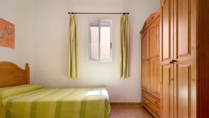 A bedroom with two beds, a window with curtains, and wooden wardrobes. - Room-casa de Vacaciones El Cardón B2 (Buenavista del Norte)