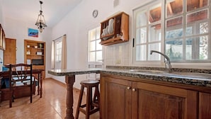 A kitchen with wooden cabinets, a granite countertop, a built-in sink, and a window with a view. - Room-casa de Vacaciones El Cardón B2 (Buenavista del Norte)