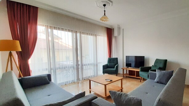 Een moderne woonkamer met grijze banken, een salontafel en een tv op een meubel.