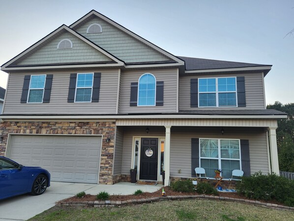 A two-story house with a stone accent wall, a garage, and a front porch with two chairs. - Great Master's retreat. 4 bedrooms. 11 miles from Augusta National (Evans)