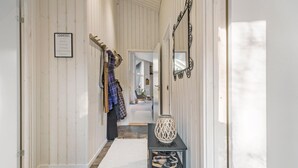 A hallway with wooden paneling, a coat rack with clothes, a shoe rack with shoes, and a decorative vase. - 5 bedroom nice home in Fårevejle (Fårevejle)