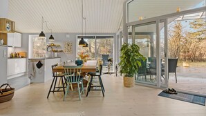 A modern kitchen with white cabinets, a wooden dining table, and pendant lights. - 5 bedroom nice home in Fårevejle (Fårevejle)