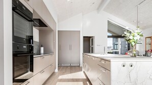 Een moderne keuken met een centraal eiland, een inbouwoven en een groot raam voor natuurlijk licht.