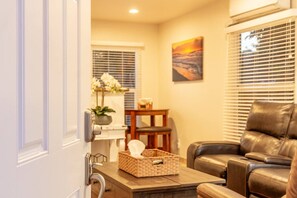 A living room with a leather sofa, a wooden coffee table, a wicker basket, and a painting on the wall. - Peace and Privacy at Bungalow among Avocado Trees (Camarillo)