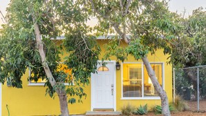 A yellow house with a white door, surrounded by trees and a fence. - Peace and Privacy at Bungalow among Avocado Trees (Camarillo)