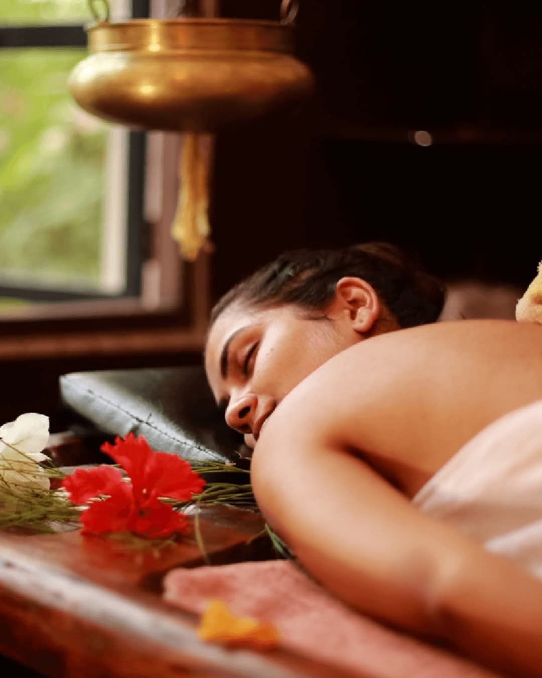 A person lying on a massage table with a lamp above them.