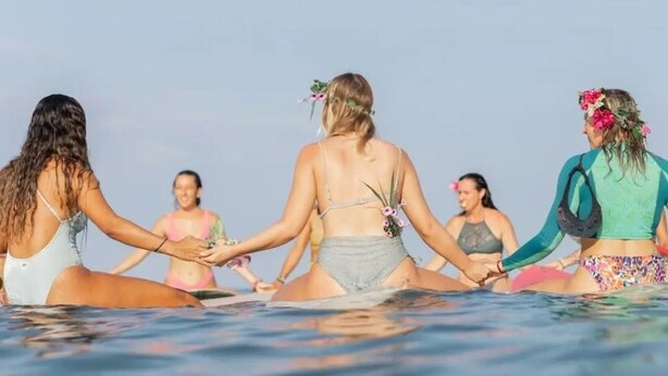 Un grupo de personas sentadas en círculo en la playa.