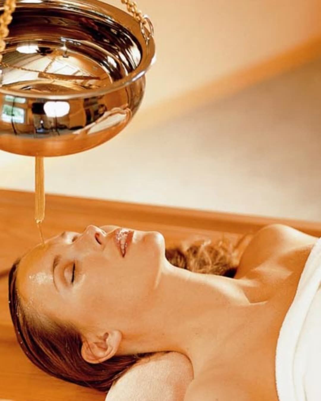 Une personne allongée, avec un récipient en métal placé au-dessus d’elle, probablement dans le cadre d’un soin de spa.