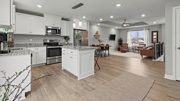 A modern kitchen with white cabinets, stainless steel appliances, and a dining area with a wooden table and chairs. - Stylish MidModern New Build w/ Extra Apartment (Grandview)