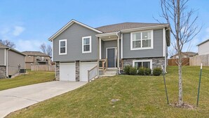 A two-story residential house with a garage, a front porch, and a small front yard. - Stylish MidModern New Build w/ Extra Apartment (Grandview)